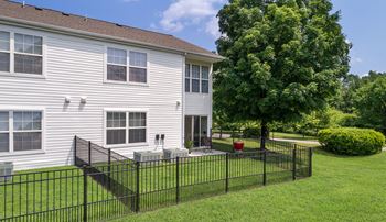 a white house with a yard with a fence and a patio